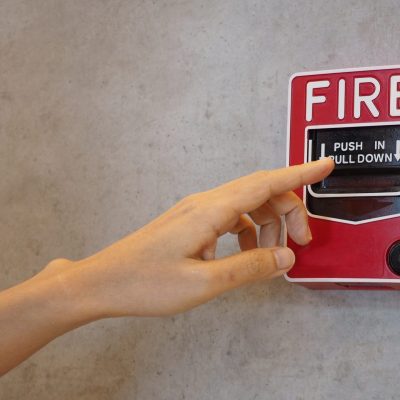 Emergency of Fire alarm or alert or bell warning equipment in red color with hand in the building for safety.