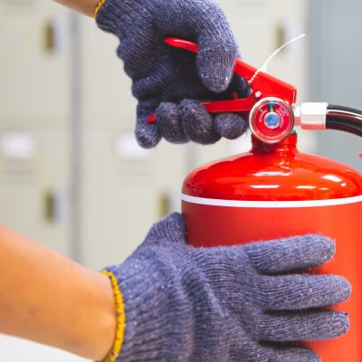Fire extinguisher has hand engineer checking handle of fire extinguishers to prepare fire equipment for protection and prevent in emergency case and safety or rescue and alarm system training concept.